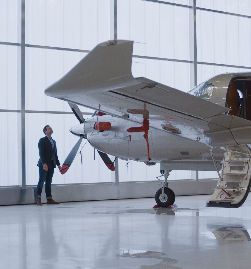 Man in a hangar looking at the propeller of a Pilatus PC-12 