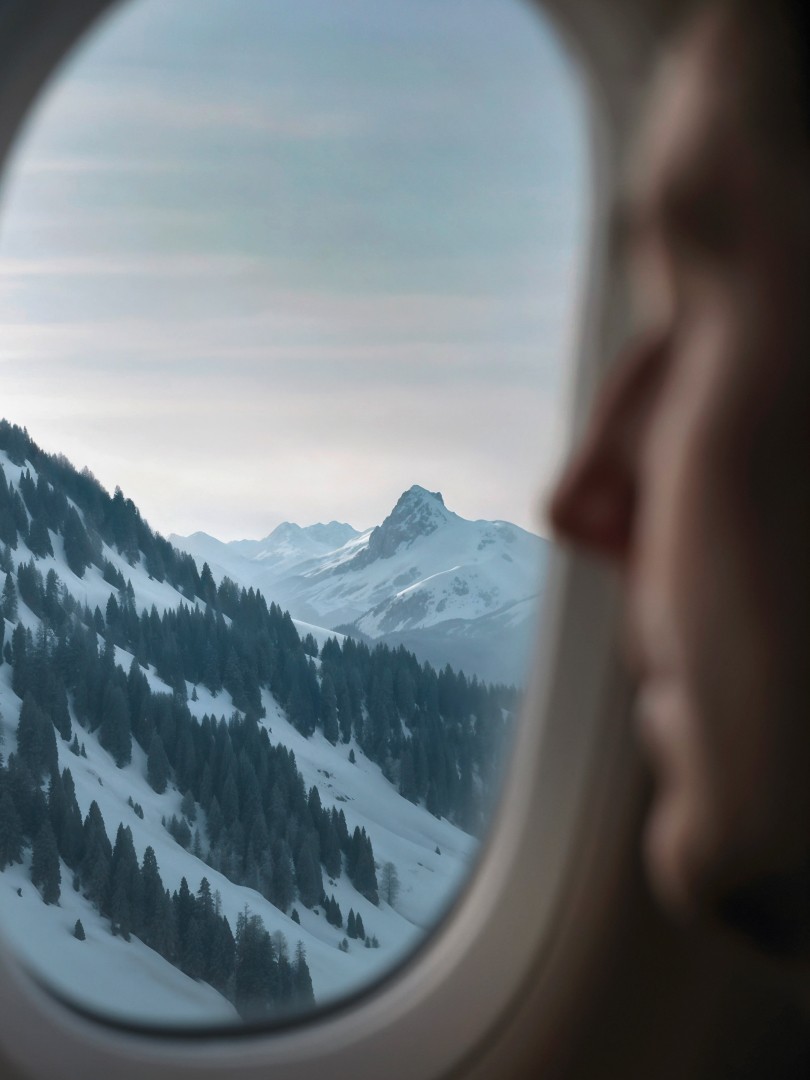 Vue de montagnes enneigées depuis le hublot d’un avion